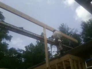 Carpenter setting a ridge beam over a new addition frame — Ice Dam Removal by Roofing Brothers in Hubbard