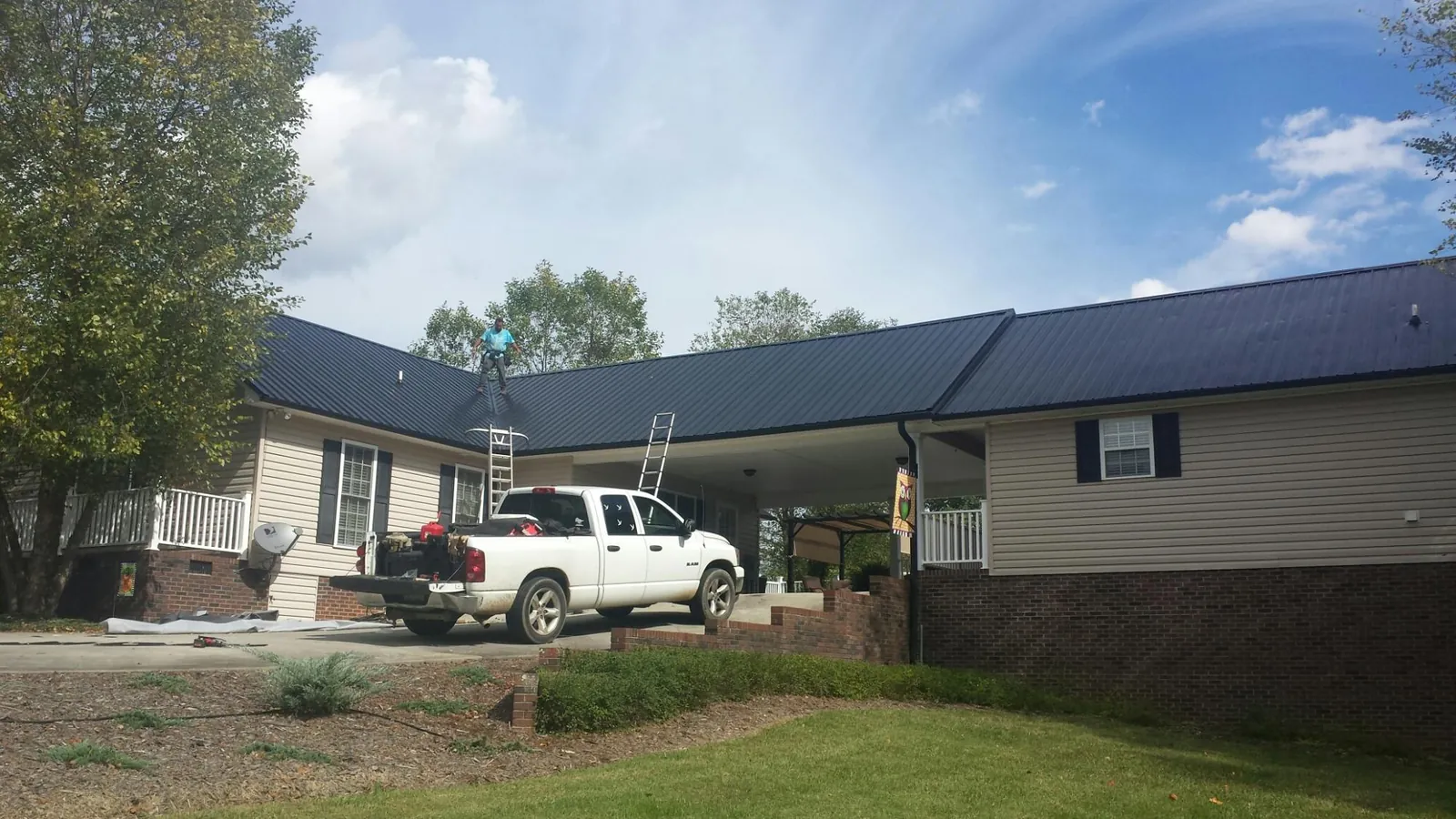 Black metal roof over a home and attached breezeway with ladders set in Hubbard