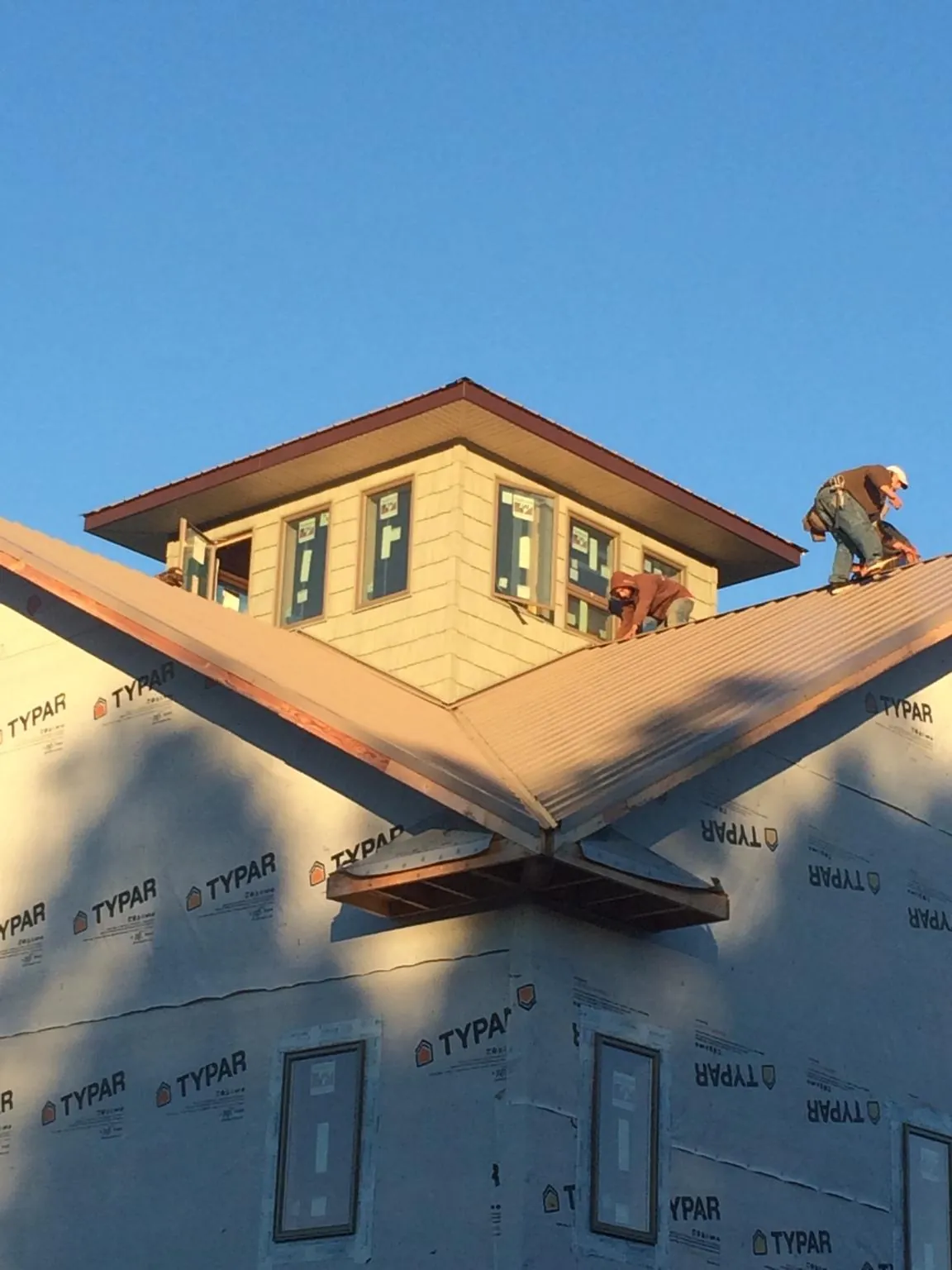 Roofers working around a rooftop cupola on a new metal roof at sunset — Roof Waterproofing in Hubbard by Roofing Brothers